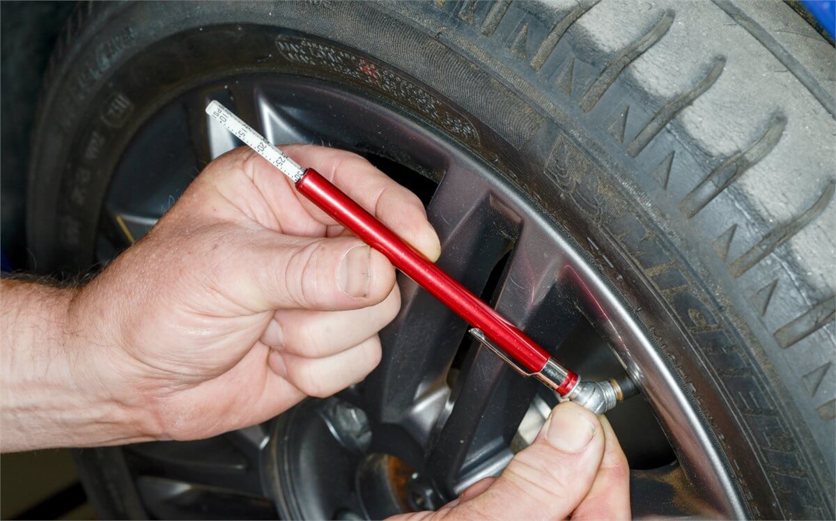 Checking car tyre pressure with a gauge